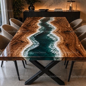 Op de afbeelding: Een grote, rechthoekige eettafel met een uniek ontwerp. Het tafelblad heeft een donker houtnerfpatroon met een centraal rivierachtig epoxyharsontwerp in tinten van blauwgroen en wit. De tafel wordt ondersteund door een zwart metalen onderstel en is omgeven door beige stoelen.