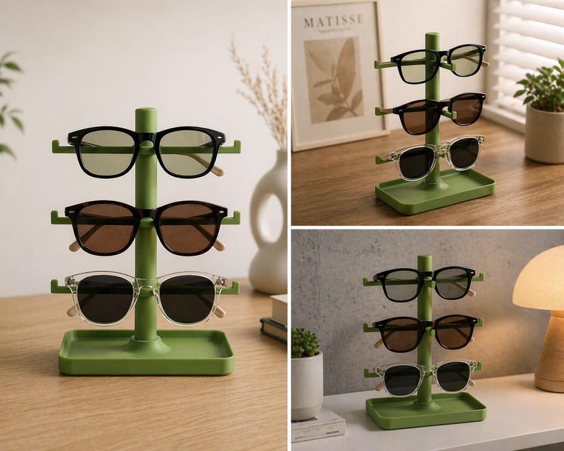May include: A green sunglasses display stand holding three pairs of sunglasses. The sunglasses have black, brown, and clear frames. The stand is made of green plastic and has a small tray at the base.