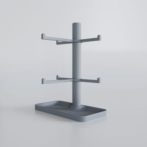 May include: A gray, tiered mug rack with a rectangular base and three levels of hooks. The central pole supports the horizontal arms, designed to hold mugs. The rack is made of a solid, matte material.