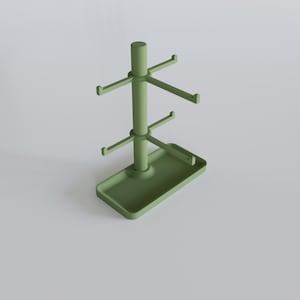 May include: A sage green mug tree with a rectangular base and multiple hooks for hanging mugs. The tree has a central pole with two tiers of hooks and a top cylindrical piece. The base has a small tray.