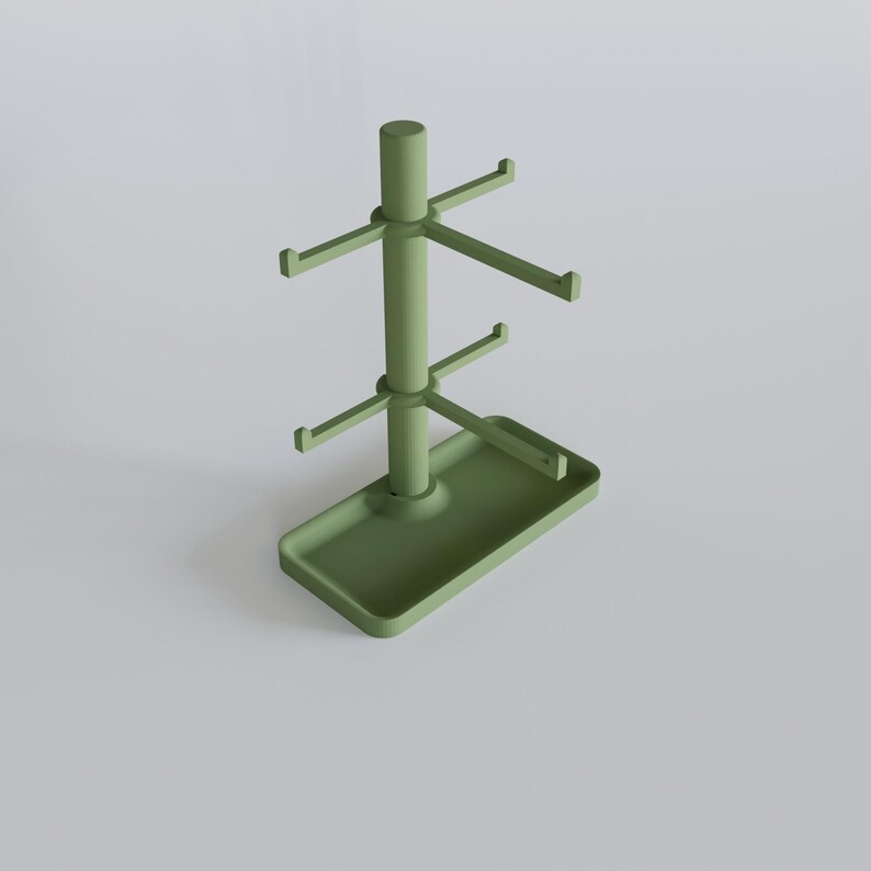 May include: A sage green mug tree with a rectangular base and multiple hooks for hanging mugs. The tree has a central pole with two tiers of hooks and a top cylindrical piece. The base has a small tray.
