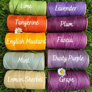 May include: Ten cylindrical spools of colored twine arranged in two columns. The left column features Lime, Tangerine, English Mustard, Mint, and Lemon Sherbet. The right column features Lavender, Plum, Fuscia, Dusty Purple, and Grape.