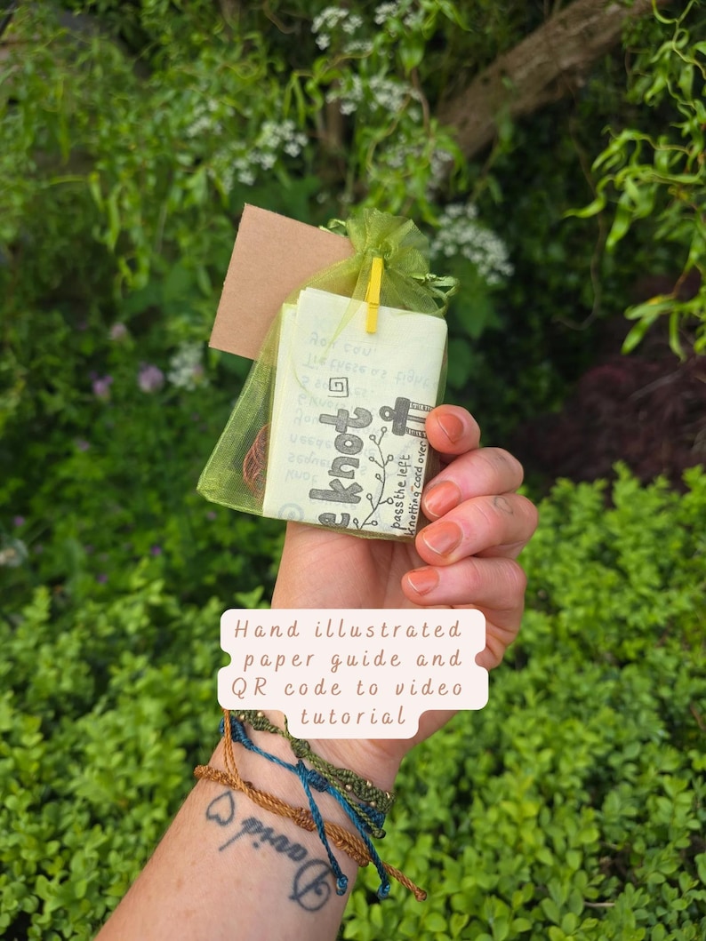 May include: A green organza drawstring pouch containing a hand-illustrated paper guide with the text "knot" and "pass the left knotting cord over". The pouch includes a small yellow clip and a brown cord, accompanied by three thin braided bracelets.