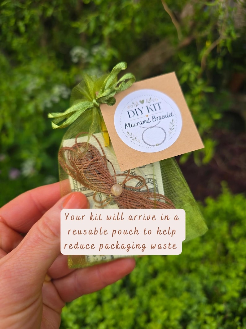 May include: A DIY macram&eacute; bracelet kit inside a sheer olive green organza drawstring pouch. A square brown tag features the text DIY KIT Macram&eacute; Bracelet and a line drawing of a bracelet. Brown cord and a single round bead are visible inside.
