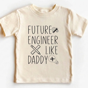 May include: A white ceramic mug with a black handle and the text "But First, Coffee" in a bold, black font. The mug is set against a blurred background, suggesting a cozy setting.