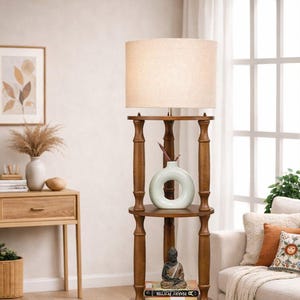 May include: A wooden floor lamp with a beige lampshade. The lamp has multiple circular shelves holding decorative items, including a light green vase, a small Buddha statue, and a yellow lantern. The lamp is in a living room setting.