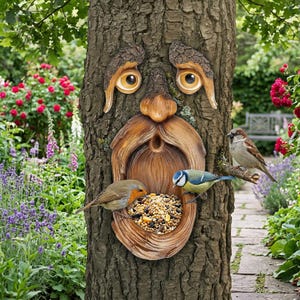 May include: A whimsical tree face bird feeder carved into a tree trunk. The feeder has a detailed face with large eyes and a beard, with three birds perched on it. The feeder is filled with birdseed, and the background shows a garden.