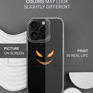 K&ouml;nnte beinhalten: Transparente Handyh&uuml;lle mit einem schwarzen und orangefarbenen Halloween-Design. Die H&uuml;lle zeigt ein l&auml;chelndes K&uuml;rbisgesicht. Der Text auf dem Bild lautet "THIS IS DURABLE UV PRINT" und "FARBEN K&Ouml;NNEN LEICHT UNTERSCHIEDLICH AUSSEHEN."