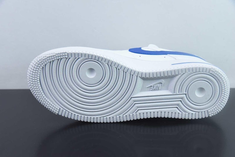 May include: White and blue athletic shoe, seen from the sole. The shoe has a white rubber sole with a circular tread pattern and the Nike logo. A blue accent stripe is visible on the upper.