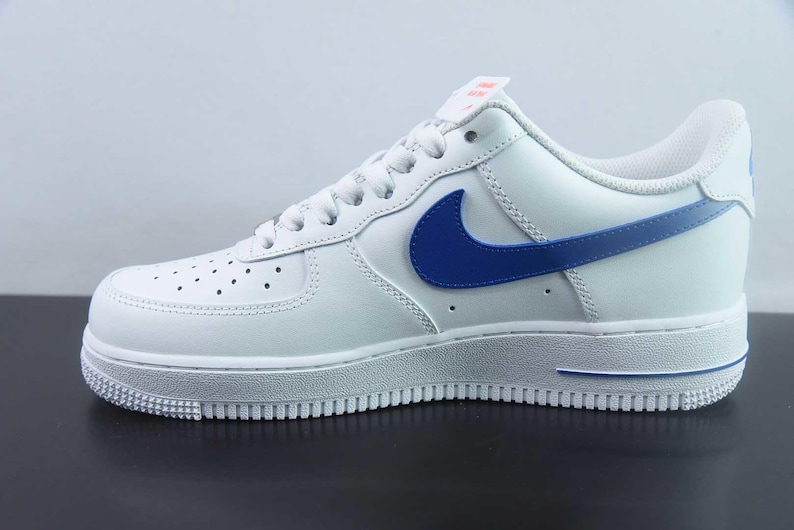 May include: White leather trainer with a blue swoosh and detailing. The shoe has a white sole and a perforated toe. A classic athletic shoe.