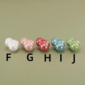 May include: Five small, glossy, cloud-shaped beads arranged in a horizontal row. The colors from left to right are white, light pink, dark pink, light blue, and light green. Below each bead are the black capital letters F, G, H, I, and J.