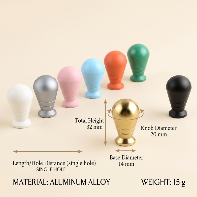 Op de afbeelding: Een collectie van enkelgats knoppen van aluminiumlegering in wit, zilver, roze, blauw, oranje, groen, goud en zwart. De gouden knop heeft labels die een totale hoogte van 32 mm, een knopdiameter van 20 mm en een basisdiameter van 14 mm aangeven.