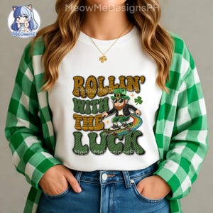 Puede incluir: Camiseta blanca con un gráfico del Día de San Patricio. El diseño presenta el texto "ROLLIN' WITH THE LUCK" y una ilustración de un duende montando un monopatín arcoíris. La camiseta se usa con una camisa a cuadros verdes y blancos.