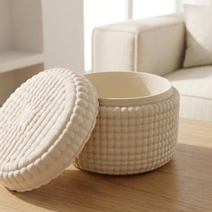 May include: A round, off-white storage container with a matching removable lid. The exterior of both the base and the lid features a uniform, raised grid-like texture composed of small, rounded, bubble-shaped bumps across the entire surface.