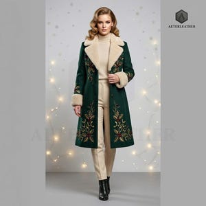 Könnte beinhalten: Ein dunkelgrüner, knielanger Mantel mit einem cremefarbenen Kunstfellkragen und Ärmelbündchen. Der Mantel ist mit gestickten Stechpalmenblättern und Beerenmotiven in rotem, goldenem und grünem Garn verziert. Er wird über einem cremefarbenen Rollkragenpullover getragen.