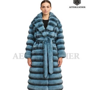 May include: A long, blue and black striped fur coat with a matching belt. The coat has a wide collar and is knee-length. The brand name "AETERLEATHER" is visible in the upper right corner.