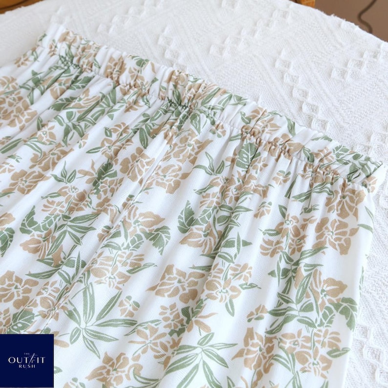 Puede incluir: Pantalones de pijama blancos con estampado floral en tonos verdes y beige. La cintura el&aacute;stica es visible en la parte superior del pantal&oacute;n. Los pantalones est&aacute;n hechos de una tela suave y ligera.