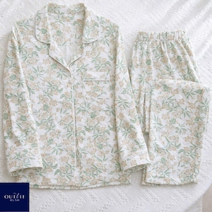 Puede incluir: Un conjunto de pijama de dos piezas con estampado floral en tonos verdes y beige sobre fondo blanco. El conjunto incluye una camisa abotonada con bolsillo en el pecho y pantal&oacute;n largo con cintura el&aacute;stica. El pijama est&aacute; hecho de tela suave y ligera.