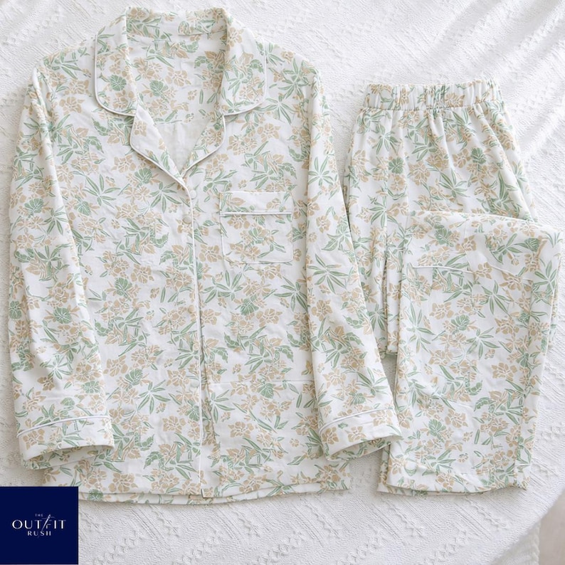 Puede incluir: Un conjunto de pijama de dos piezas con estampado floral en tonos verdes y beige sobre fondo blanco. El conjunto incluye una camisa abotonada con bolsillo en el pecho y pantal&oacute;n largo con cintura el&aacute;stica. El pijama est&aacute; hecho de tela suave y ligera.