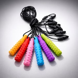 Peut inclure: Un ensemble de cordons de lunettes colorés. Chaque cordon est d'une couleur différente, notamment orange, rouge, rose, bleu, violet et vert. Les cordons ont une surface texturée et pointillée et sont attachés à un cordon noir.