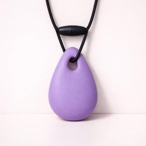May include: A lavender teardrop pendant necklace with a black cord and clasp. The pendant has a smooth, rounded form with a hole at the top. The necklace is displayed against a white background.