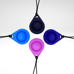 Könnte beinhalten: Vier farbige, tropfenförmige Silikon-Accessoires in Blau, Lila und Marineblau, jedes mit einer kreisförmigen Vertiefung und einer schwarzen Kordel. Die Accessoires sind symmetrisch vor weißem Hintergrund angeordnet.