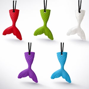 May include: Five colorful mermaid tail pendants in red, green, white, purple, and blue. Each pendant is suspended by a black cord. The tails have a textured, scaled design and are a whimsical accessory.