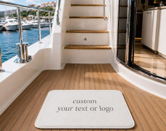 Puede incluir: Una alfombrilla rectangular blanca con esquinas redondeadas que presenta el texto gris custom your text or logo centrado en la superficie. La alfombrilla está colocada sobre la cubierta de madera de un barco con escaleras blancas y una barandilla.