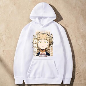 May include: A white long-sleeve hooded sweatshirt featuring a graphic print of the anime character Himiko Toga with blonde hair and yellow eyes. The design includes Japanese text, the name Himiko Toga, and the words Knives in a tan color.