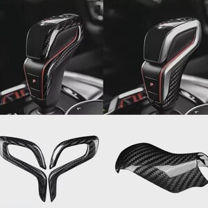 May include: A collection of car interior accessories, including a gear shift knob and trim pieces. The gear shift knob is black with a carbon fibre pattern and red accents. The trim pieces also feature a carbon fibre design. These items are for automotive customisation.