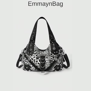 Puede incluir: Un bolso de mano en blanco y negro con un diseño de estampado de leopardo y cebra. El bolso tiene dos asas y una correa para el hombro. El texto "EmmaynBag" está en la parte superior de la imagen. Tiene herrajes plateados y una hebilla decorativa.