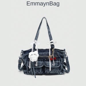 Puede incluir: Bolso de mano de mezclilla azul oscuro con correa para el hombro y dos bolsillos delanteros. El bolso está decorado con un charm de nube blanca y un llavero de cerezas. El texto "EmmaynBag" está en la parte superior.