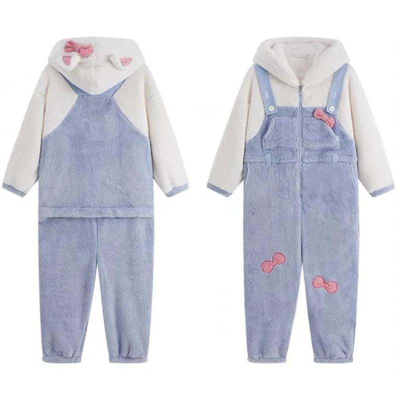 May include: Two-piece and one-piece pajama sets. The sets are made of soft, plush material in white and light blue. The two-piece set has a hooded top with cat ears and a pink bow. The one-piece set has a hood, a front pocket, and pink bow accents.