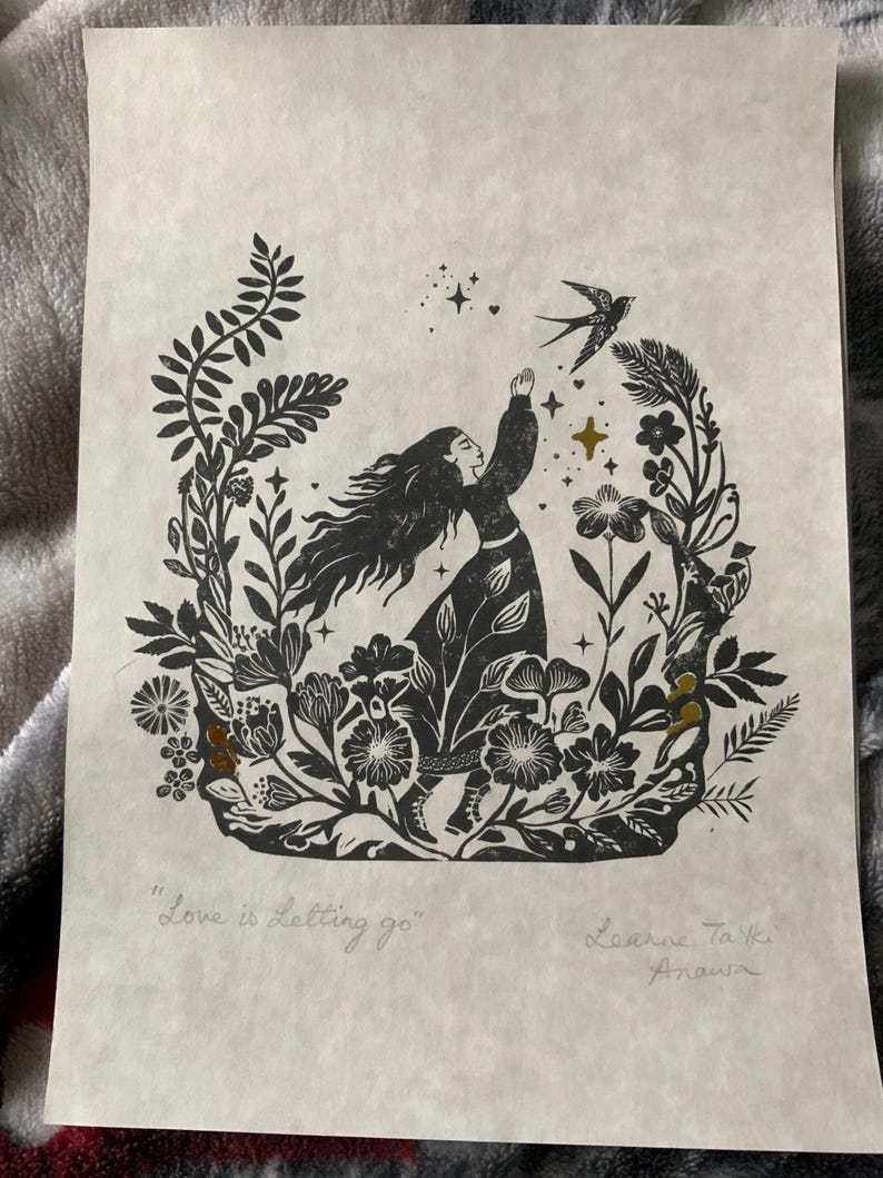 May include: Black and white linocut print featuring a woman reaching for a bird, surrounded by floral elements. The print includes the text "Love is Letting go" and artist's signature. The artwork has a vintage aesthetic.