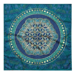 Puede incluir: Textil cuadrado con un estampado floral azul y turquesa. El centro presenta un diseño geométrico dorado y azul, rodeado por un círculo azul oscuro y un borde turquesa con puntos dorados. El diseño general es simétrico.