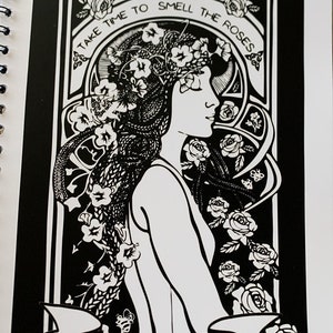 May include: Black and white coloring book cover featuring an Art Nouveau style illustration of a woman with roses in her hair. The text "Take time to smell the roses" is written in a decorative font around the woman's head. The book is published by Spirit of Lemuria.