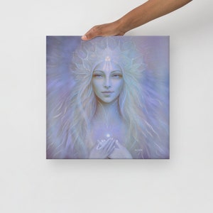 Peut inclure: Impression sur toile carrée représentant une femme aux longs cheveux blonds et à une couronne délicate. L'œuvre d'art est réalisée dans des tons doux de bleu et de blanc, avec une aura lumineuse autour de la figure. La femme tient ses mains sur sa poitrine.