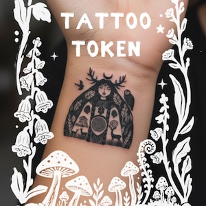 May include: A black ink temporary tattoo on skin featuring a central figure with antlers, a crescent moon, and an owl. The design includes a labyrinth, deer, and mushrooms. The text TATTOO TOKEN is printed in white above the tattoo, framed by white botanical illustrations of flowers and mushrooms.