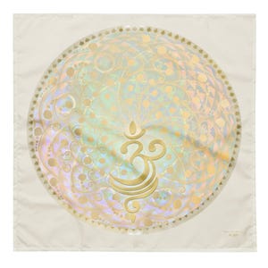 Puede incluir: Una tela cuadrada blanca con un diseño de mandala dorado que presenta un símbolo Om en el centro. El mandala tiene un acabado iridiscente.
