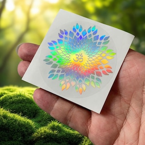 Op de afbeelding: Een witte sticker met een holografisch regenboogmandala-ontwerp met het Om-symbool in het midden.