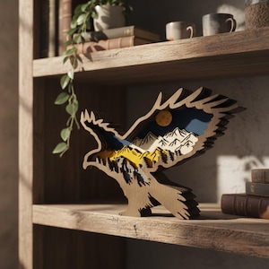 May include: A wooden eagle sculpture with a layered design, featuring a mountain and moon landscape in shades of yellow, blue, and white. The eagle is perched on a wooden shelf, showcasing a nature-themed decorative item.
