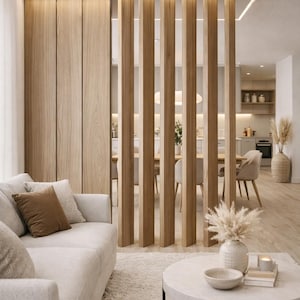 May include: A room divider featuring vertical light wood slats extending from floor to ceiling, positioned between a living area with a light-coloured sofa and a dining space. The structure includes a solid wood panel section and integrated lighting.