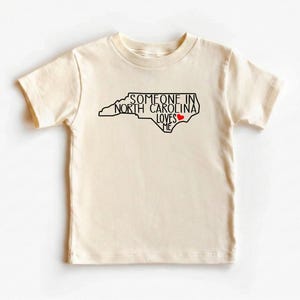 Body para bebé con el mensaje "Alguien en Carolina del Norte me ama", camiseta adorable para bebé, regalos para baby shower, camiseta para bebé con el mensaje "Amado", body para bebé con el estado, camiseta natural para bebé. imagen 3