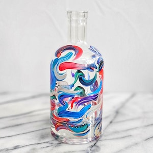 May include: A clear glass bottle with a colorful abstract design painted on the surface. The design features swirls of blue, red, green, purple, and white paint.