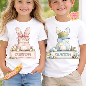 May include: White t-shirts with bunny designs. One bunny has a pink bow and floral accents, the other wears a baseball cap. Both shirts have a "CUSTOM" sign at the bottom. The designs are pastel colors.