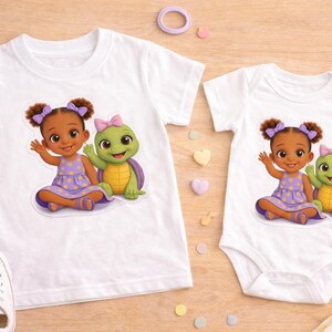 May include: White t-shirts and a onesie featuring a cartoon girl in a purple dress with a turtle. The girl has brown hair and is waving. The turtle is green with a yellow shell and a pink bow.