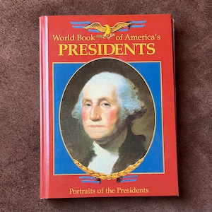 May include: A red hardcover book titled "World Book of America's Presidents" with a portrait of George Washington. The cover features a blue border and gold accents, including an eagle and laurel wreath. The book is a collection of presidential portraits.