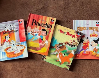 May include: Four colorful children's books featuring Disney characters. The books are titled "101 Dalmatians", "Pinocchio", "The Fox and the Hound", and "The Prince and the Pauper".