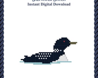 May include: A cross-stitch pattern featuring a dark blue loon with white spots, a red eye, and a tan beak, floating on light blue water. The text reads Saltwater Stitch Instant Digital Download, framed by a dark blue rope border.