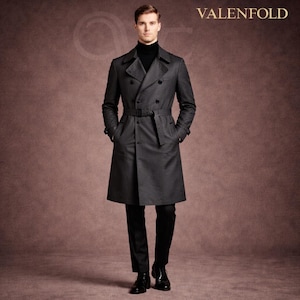 Puede incluir: Un abrigo tipo trinchera gris carbón de doble botonadura con cinturón, usado sobre un cuello alto negro y pantalones negros. El abrigo tiene un diseño clásico con cuello con muescas y detalles de botones. La marca "VALENFOLD" se muestra en la esquina superior derecha.